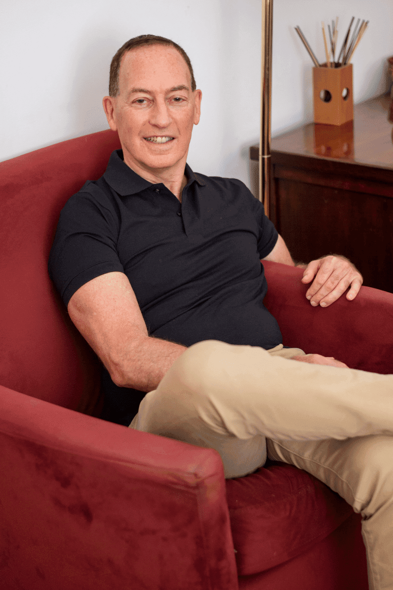 Jim Arnoff seated indoors in a red velvet chair
